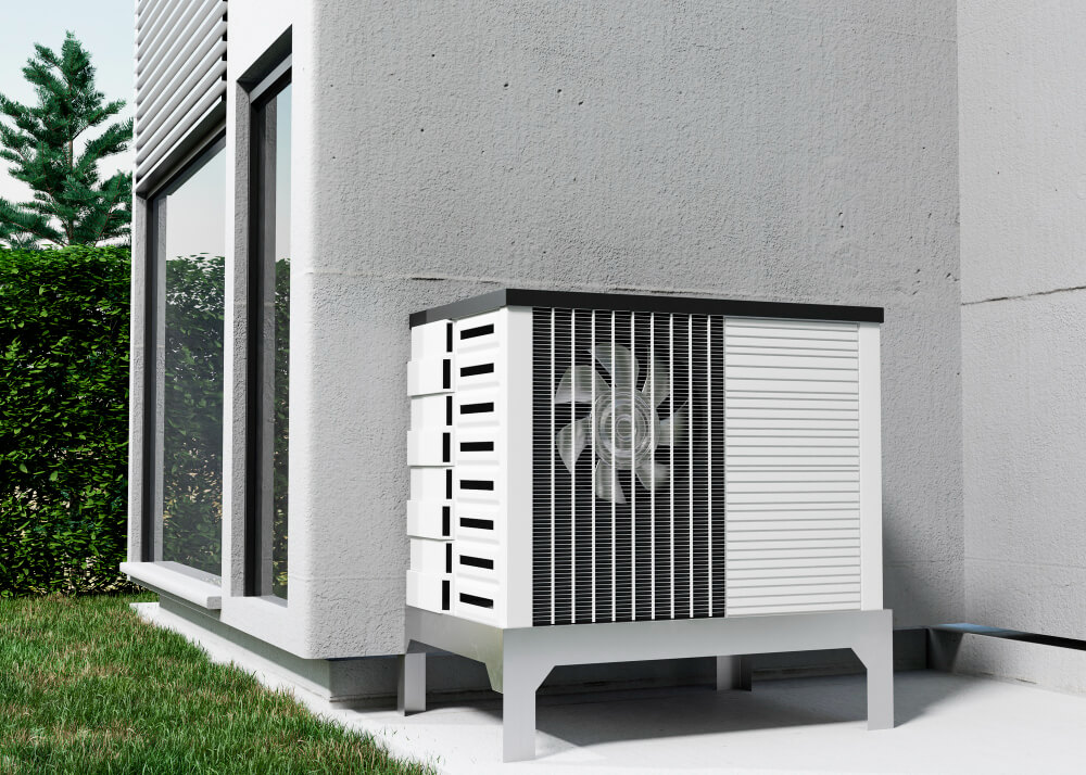 Eine moderne Wärmepumpe steht vor einem Haus mit großen Fenstern, umgeben von Rasen und Büschen