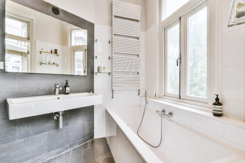 Modernes Bad mit weißer Badewanne, wandhängendem Waschbecken und großem Spiegel als automatisch gespeicherter Entwurf für Stil und Helligkeit
